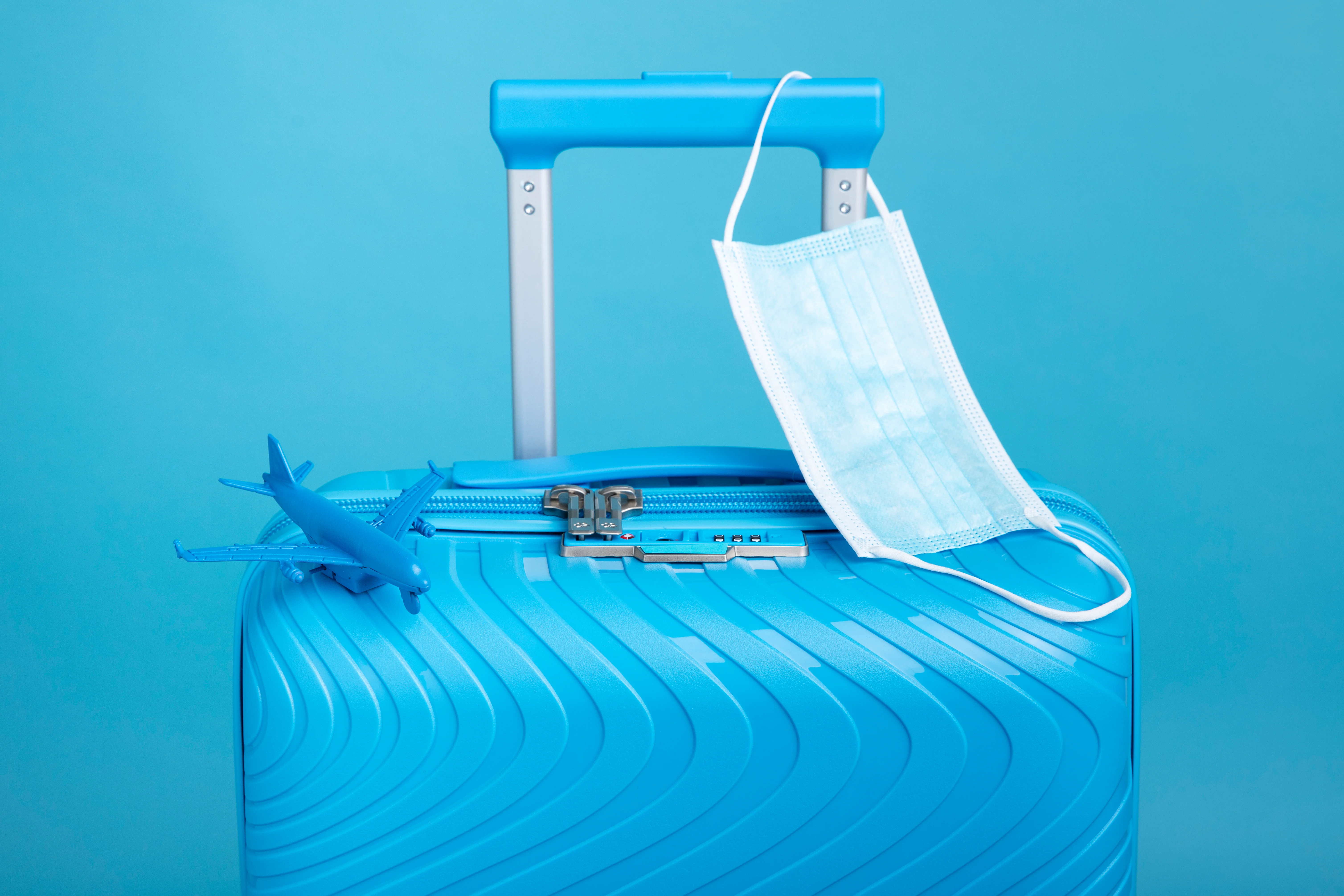 blue suitcase travel with medical mask