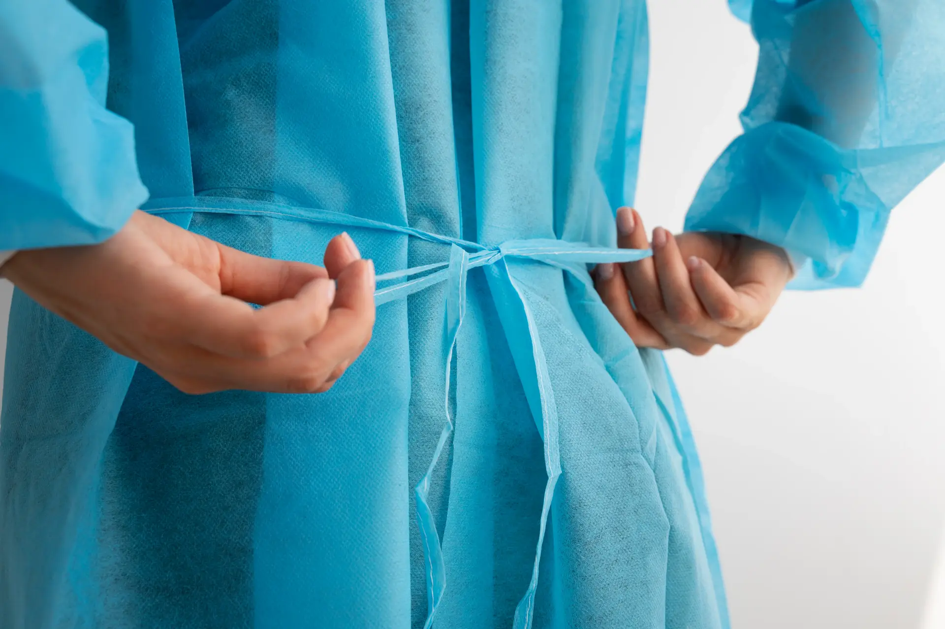 doctor tying medical gown strap side view