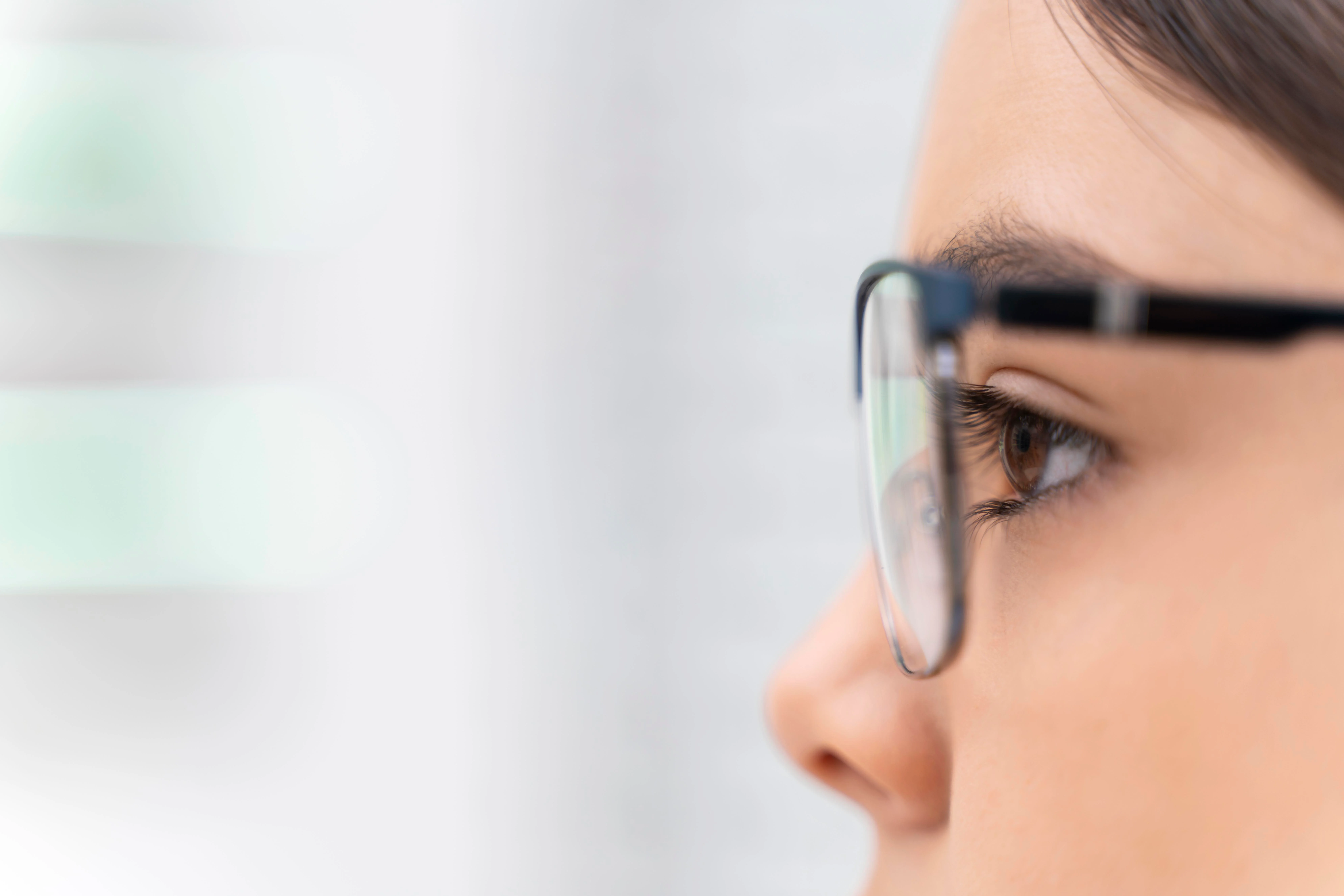 Close-up of a girl trying on a pair of glasses in a store.